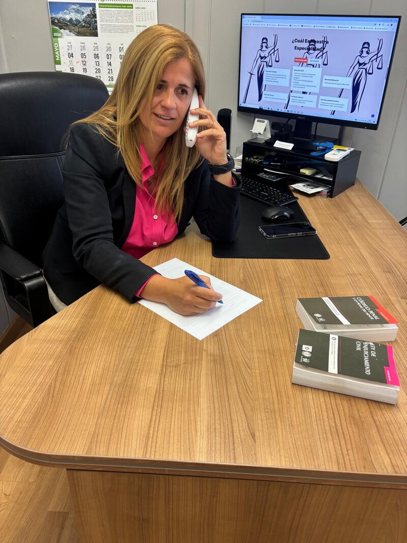 Teresa Castillo hablando por teléfono en su despacho con códigos legales